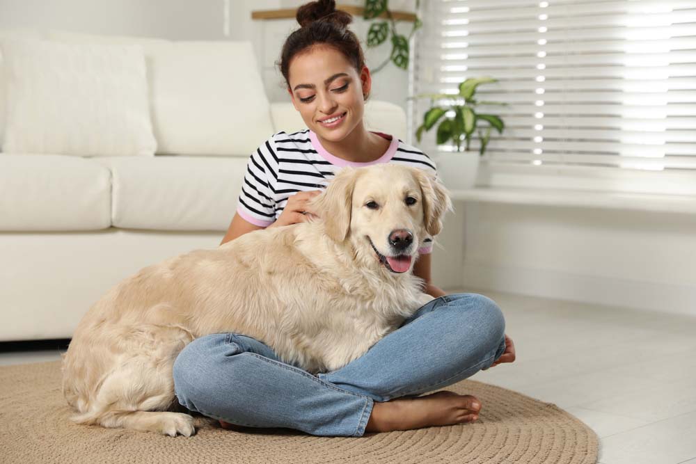 a young woman sitting on the floor with her golden retriever dog in her lap